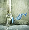 Vignette : Petit poisson bleu sautant dans une canalisation de rue - Graph'mur photographié par Norbert Pousseur - ©